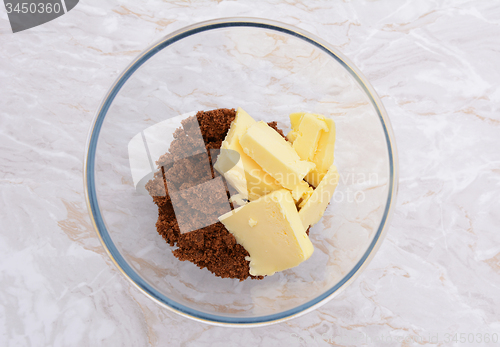 Image of Pats of butter with dark soft sugar in a bowl