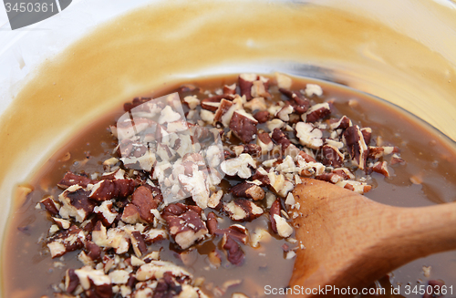 Image of Wooden spoon stirring pecan nuts into pie filling