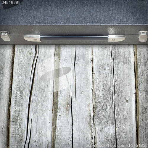 Image of Old black suitcase on the wooden floor