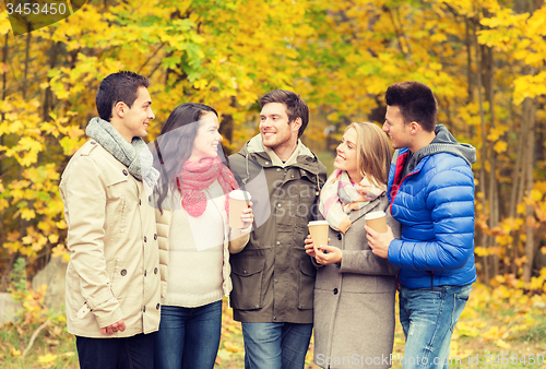 Image of group of smiling friend with coffee cups in park