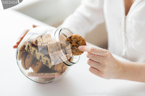 Image of close up of hands with chocolate cookies in jar