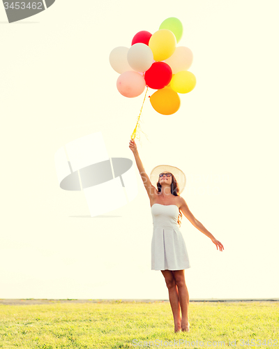 Image of smiling young woman in sunglasses with balloons