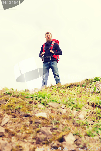 Image of tourist with beard and backpack raising hands