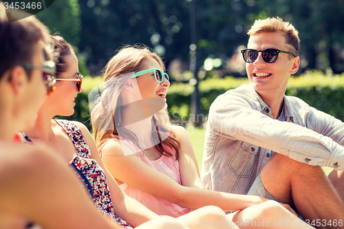 Image of group of smiling friends outdoors sitting in park