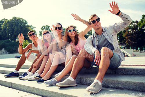 Image of group of smiling friends sitting on city street