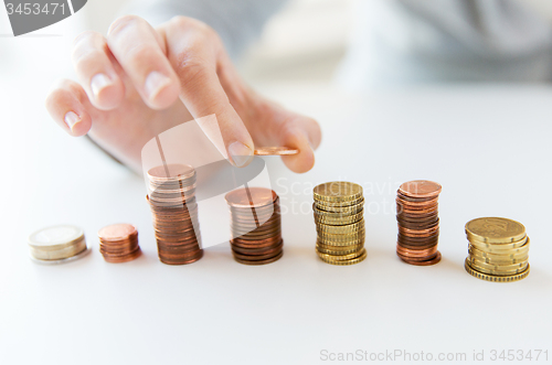 Image of close up of female hand putting coins into columns