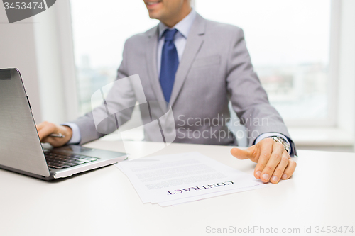 Image of close up of businessman with laptop and papers