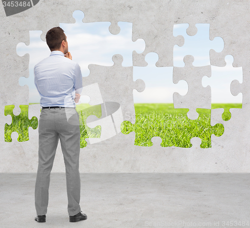Image of businessman over puzzle with natural landscape