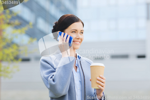 Image of smiling woman with coffee calling on smartphone
