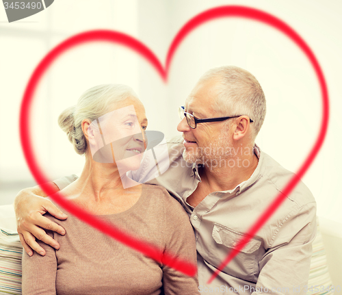 Image of happy senior couple hugging on sofa at home