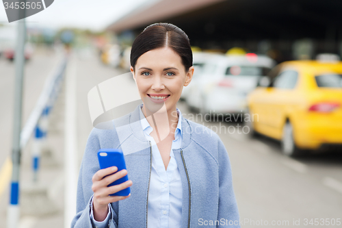 Image of smiling woman with smartphone over taxi in city