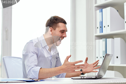 Image of angry businessman with laptop and papers in office