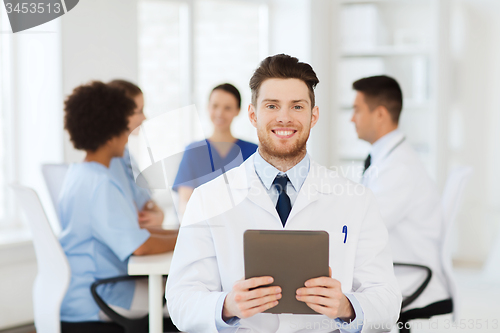 Image of happy doctor with tablet pc over team at clinic