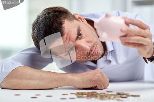 Image of businessman with piggy bank and coins at office