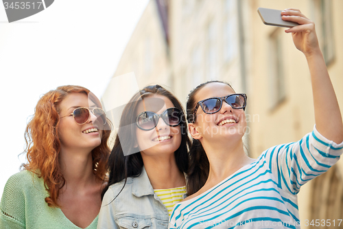 Image of smiling young women taking selfie with smartphone