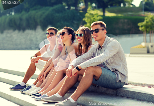 Image of group of smiling friends sitting on city square