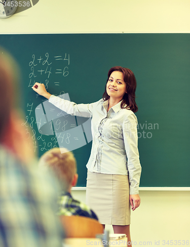 Image of school kids and teacher writing on chalkboard