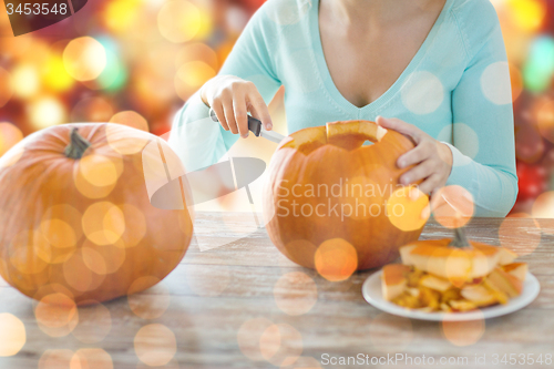 Image of close up of woman carving pumpkins for halloween