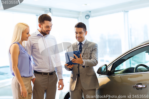 Image of happy couple with car dealer in auto show or salon