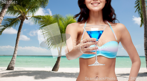 Image of happy young woman in swimsuit drinking cocktail