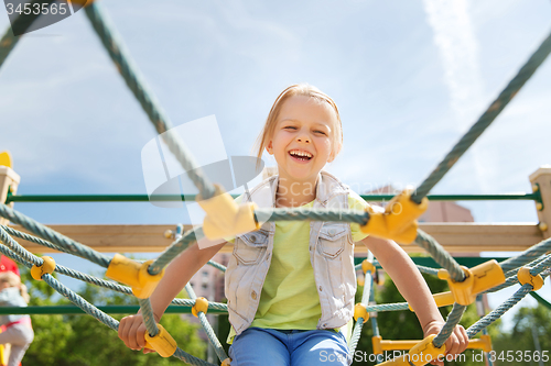Image of happy little girl climbing on children playground