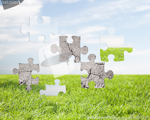 Image of concrete puzzle over blue sky and grass background