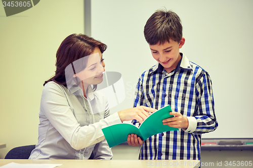 Image of school boy with notebook and teacher in classroom