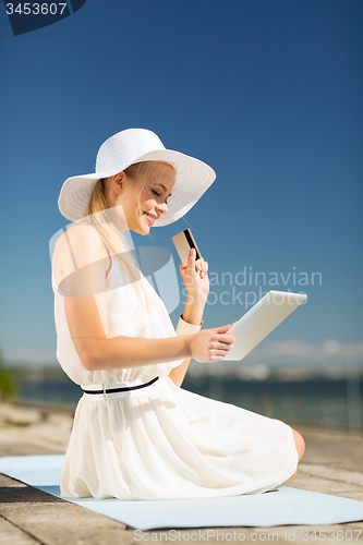 Image of woman in hat doing online shopping outdoors