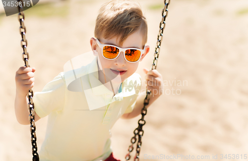 Image of happy little boy swinging on swing at playground