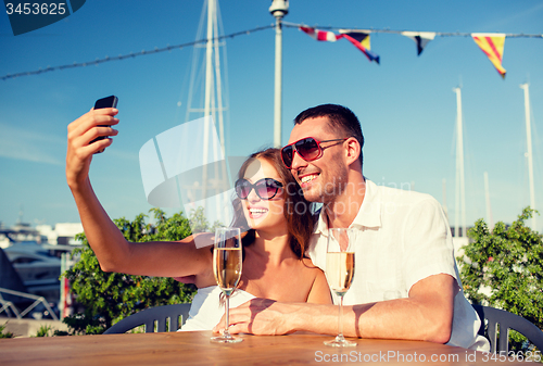 Image of smiling couple drinking champagne at cafe