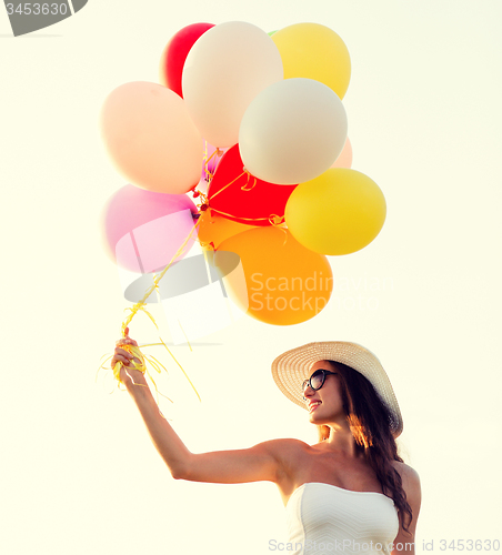 Image of smiling young woman in sunglasses with balloons