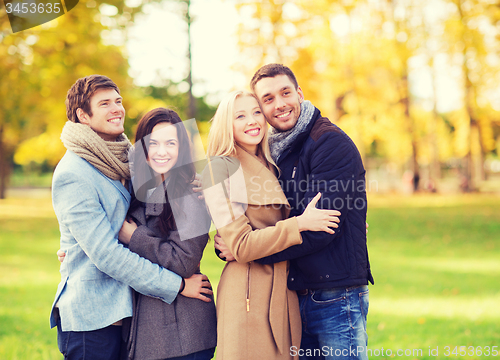 Image of group of smiling men and women in autumn park