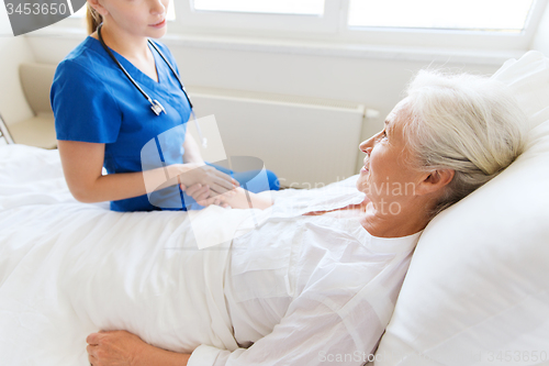 Image of doctor or nurse visiting senior woman at hospital
