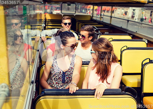 Image of group of smiling friends traveling by tour bus