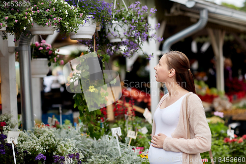 Image of pregnant woman choosing flowers at street market