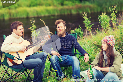 Image of group of tourists playing guitar in camping