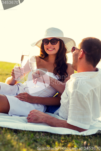 Image of smiling couple drinking champagne on picnic