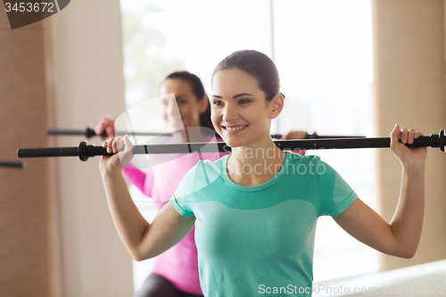 Image of group of people exercising with bars in gym