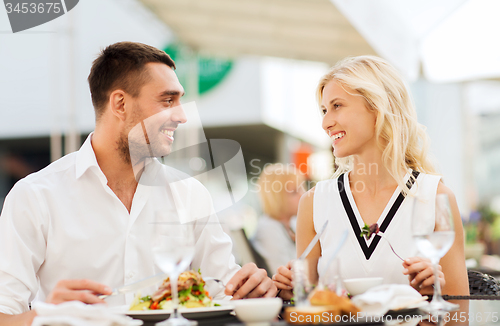 Image of happy couple eating dinner at restaurant terrace