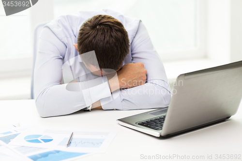 Image of businessman with laptop and papers in office