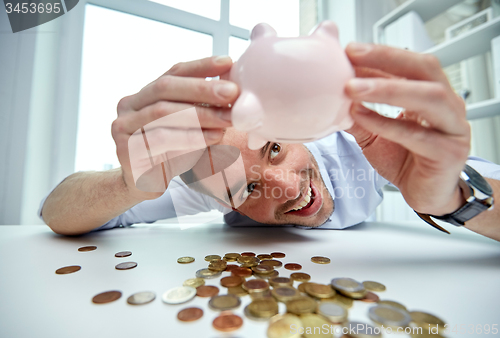 Image of businessman with piggy bank and coins at office