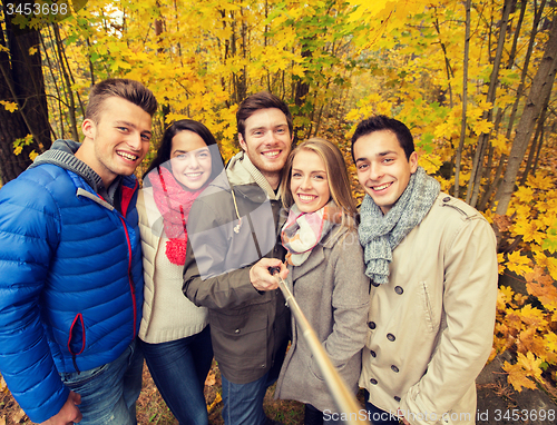 Image of smiling friends with smartphone in city park