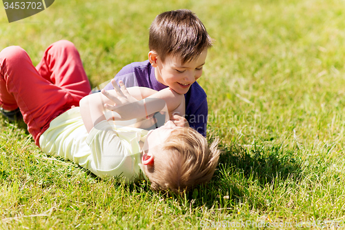 Image of happy little boys fighting for fun on grass