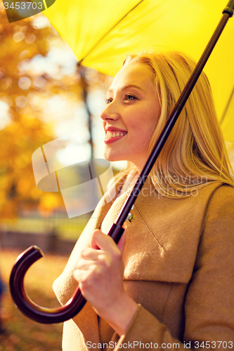 Image of smiling woman with umbrella in autumn park