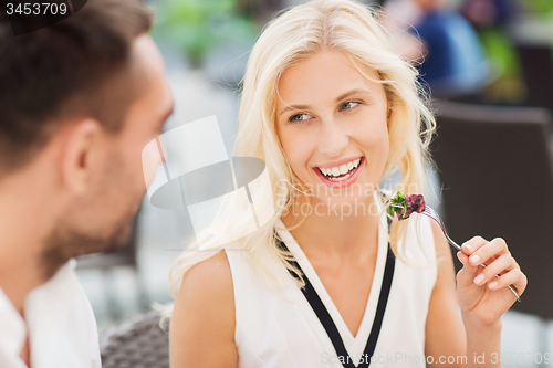 Image of happy couple eating dinner at restaurant terrace