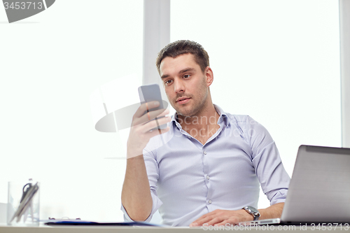 Image of businessman with smartphone and laptop at office