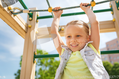 Image of happy little girl climbing on children playground