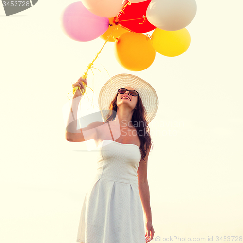 Image of smiling young woman in sunglasses with balloons