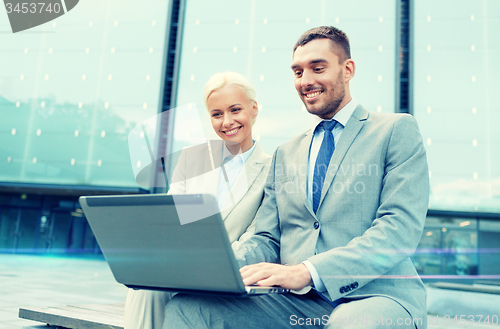 Image of smiling businesspeople with laptop outdoors