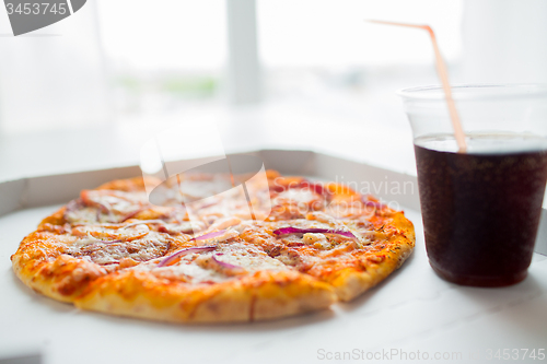 Image of close up of pizza with cola on table